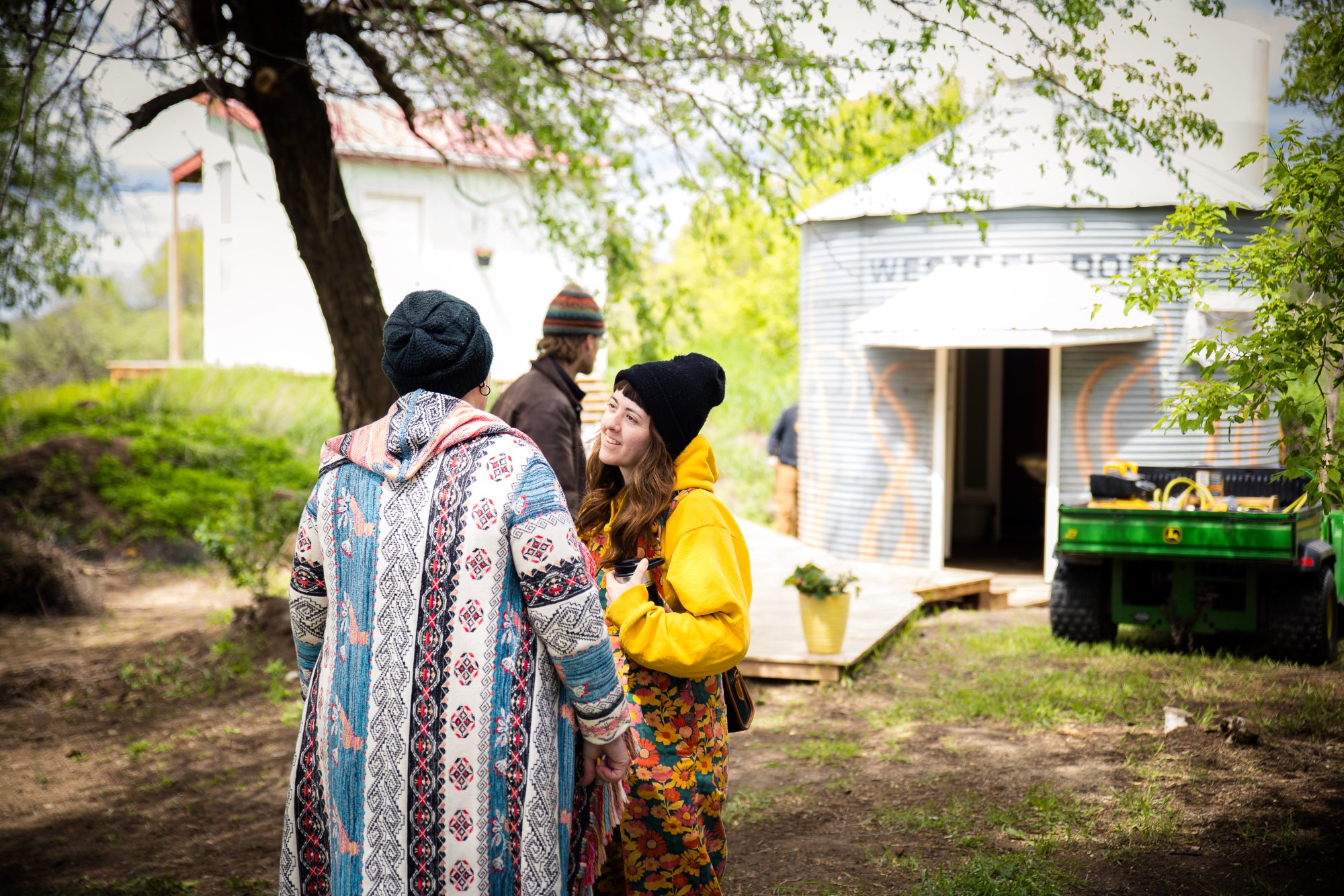 Two guests at Wiebe Works — candid moment with the grain bin and farm buildings behind them