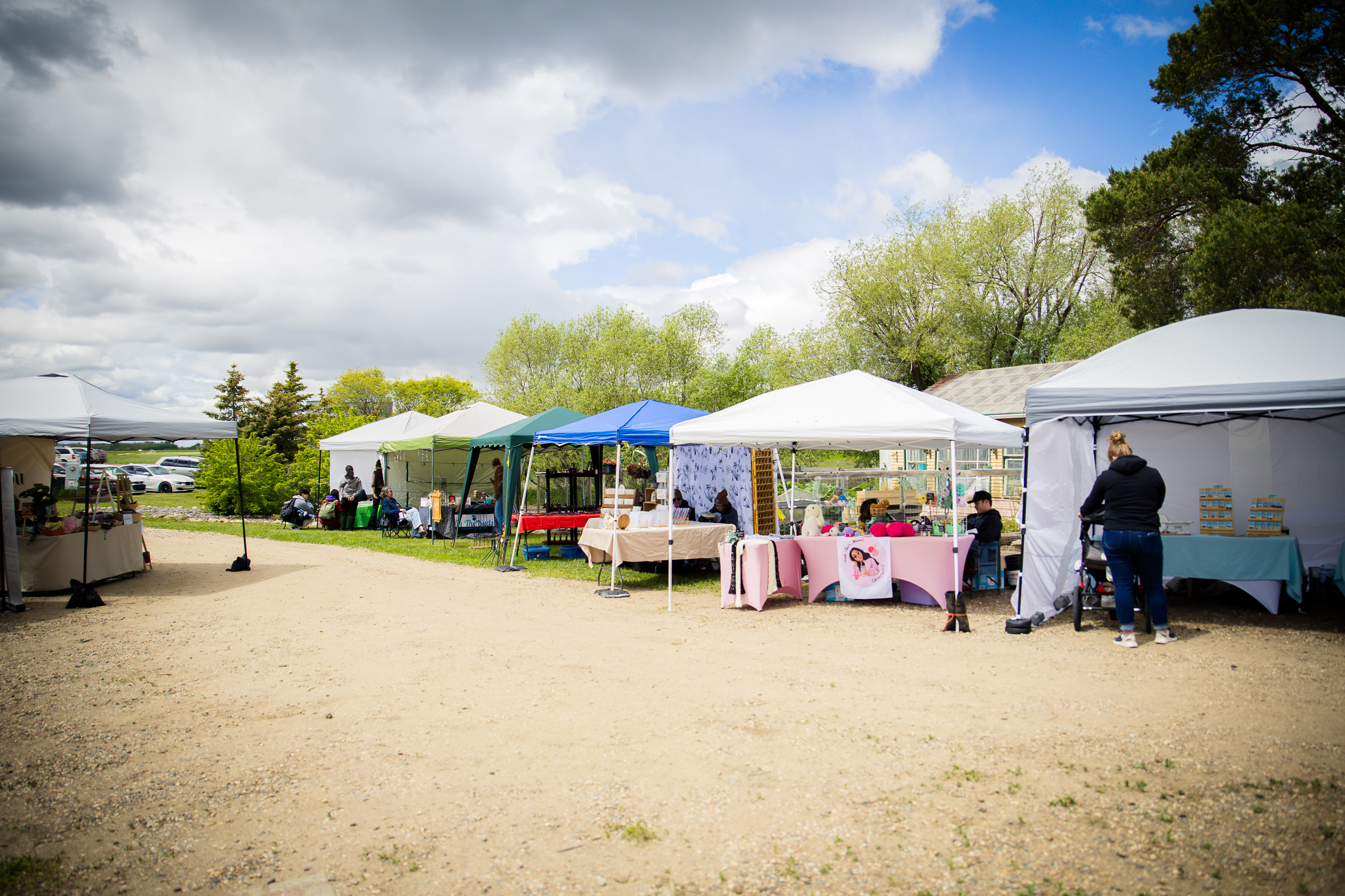 Row of vendor tents at the Art in the Garden artisan market — prairie sky in the background