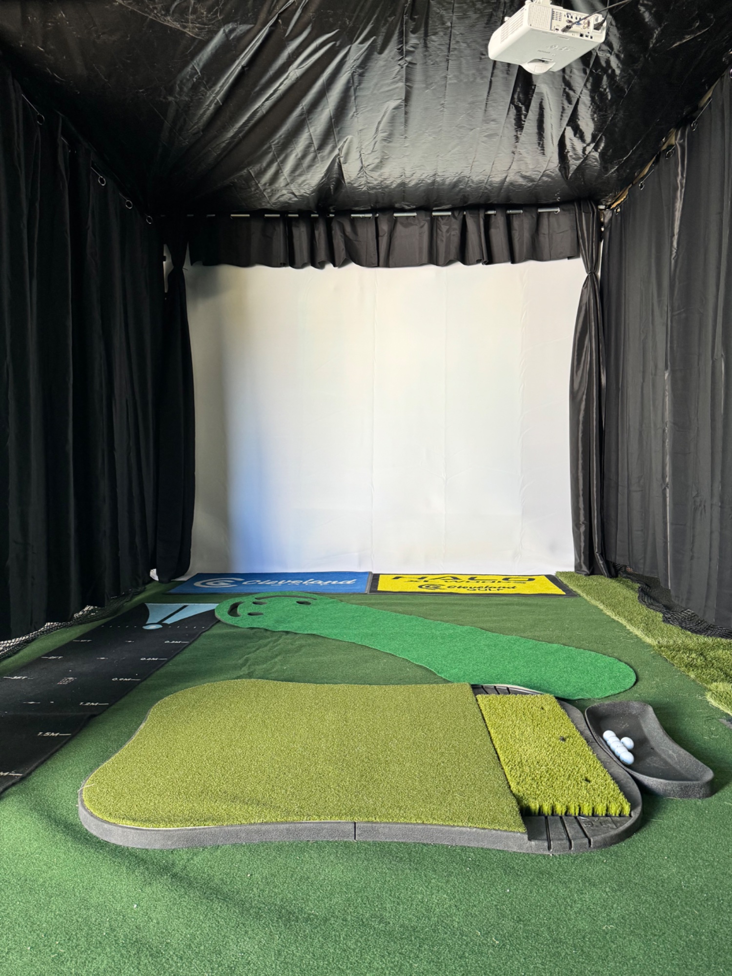 SwingDen simulator bay interior — projector, impact screen, hitting mat and Cleveland Golf branding in Warsaw, Virginia