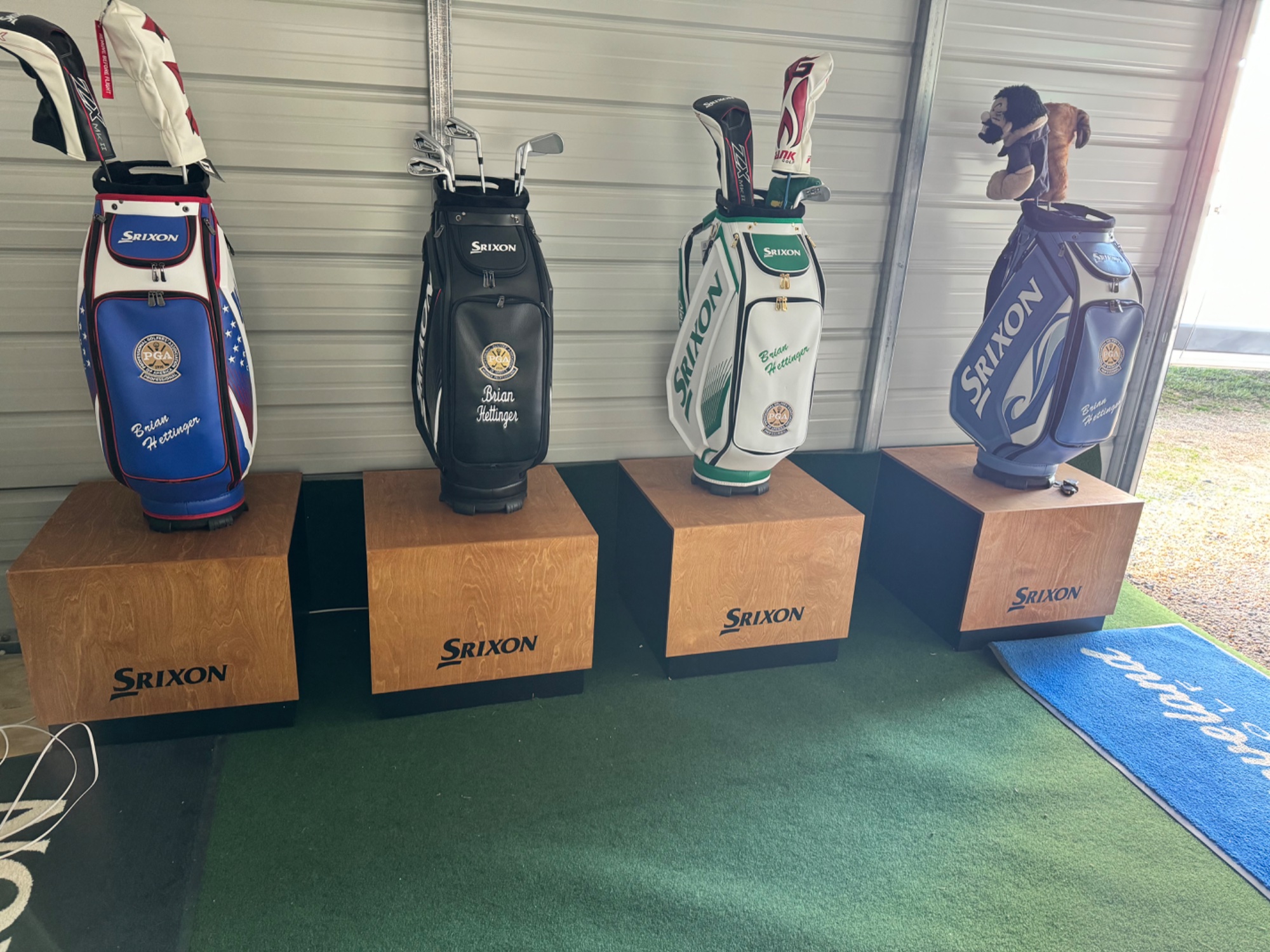 Four personalized Srixon golf bags on custom wooden pedestals at SwingDen