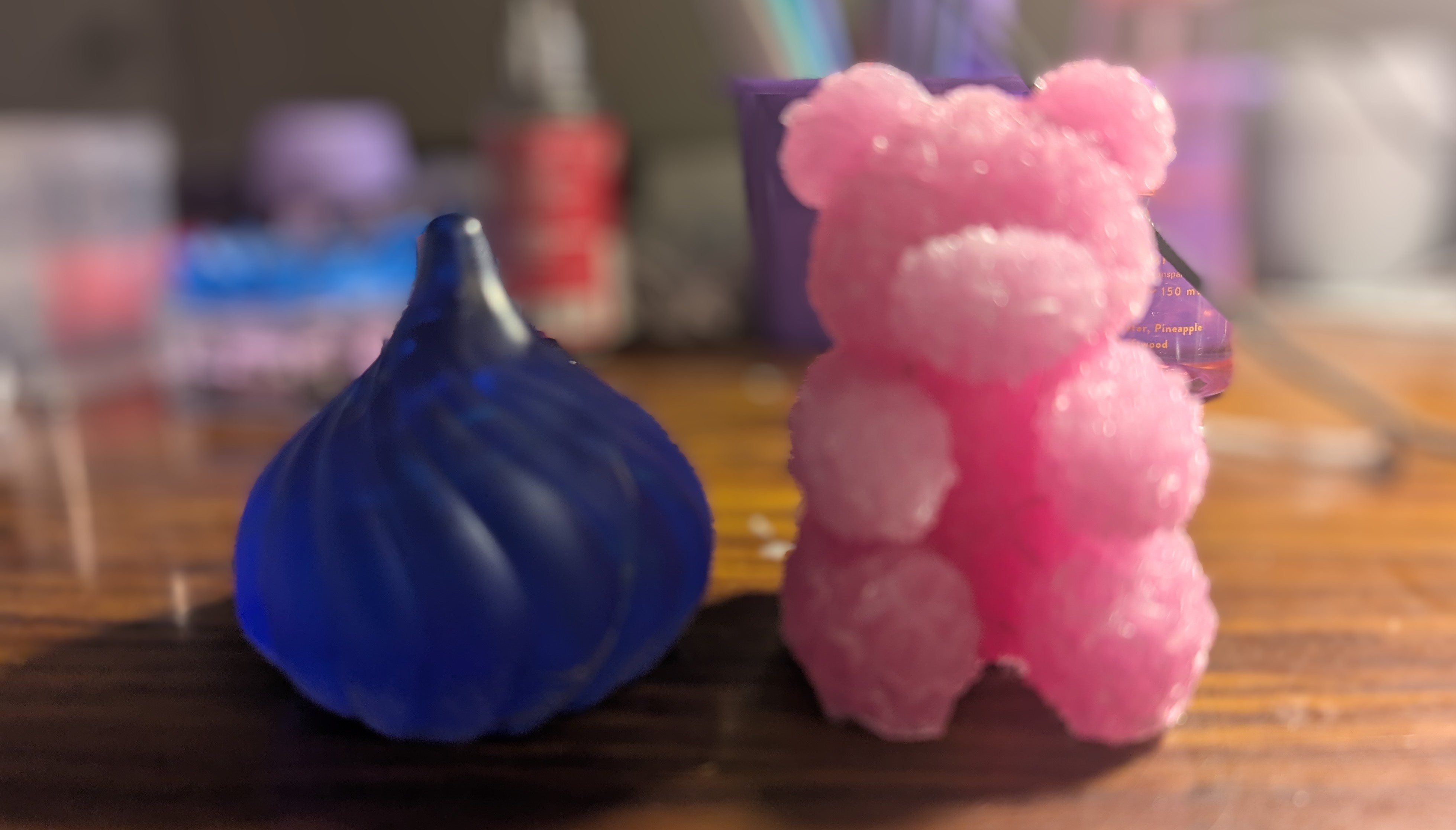 Handmade blue resin teardrop and pink rose bear sculptures in natural light