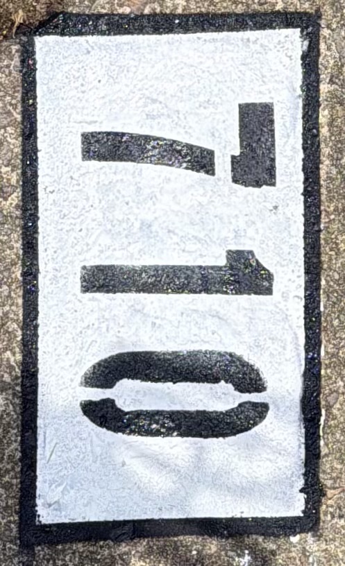 Curb painting completed — bold address numbers on curb
