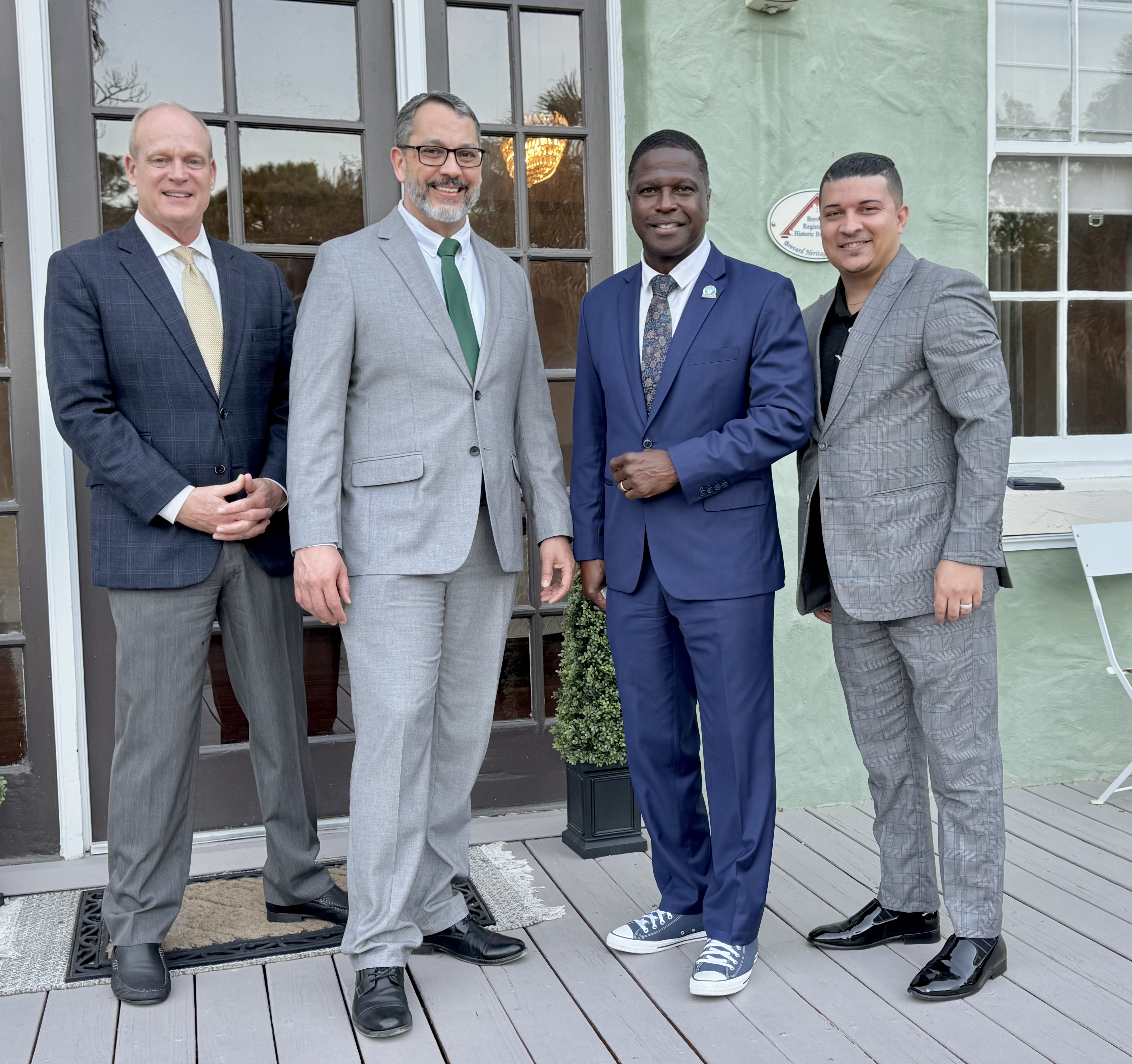 Four suited professionals outside event venue