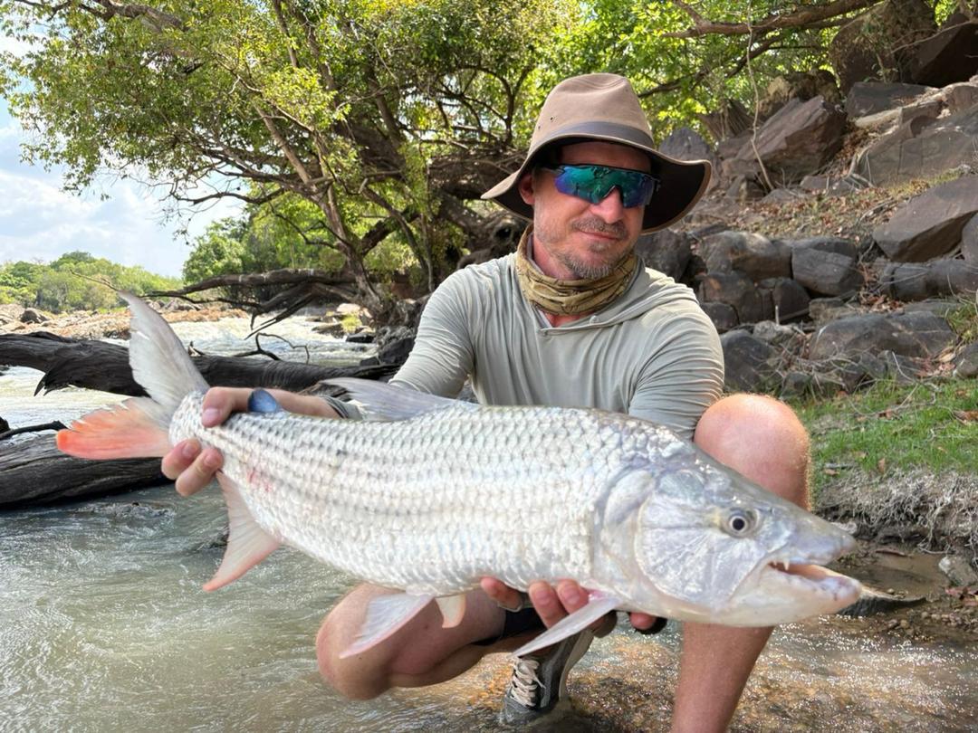 Angler with tigerfish on rocky riverbank