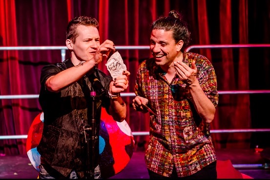 Foggy Jack performing with an audience participant under red stage lights