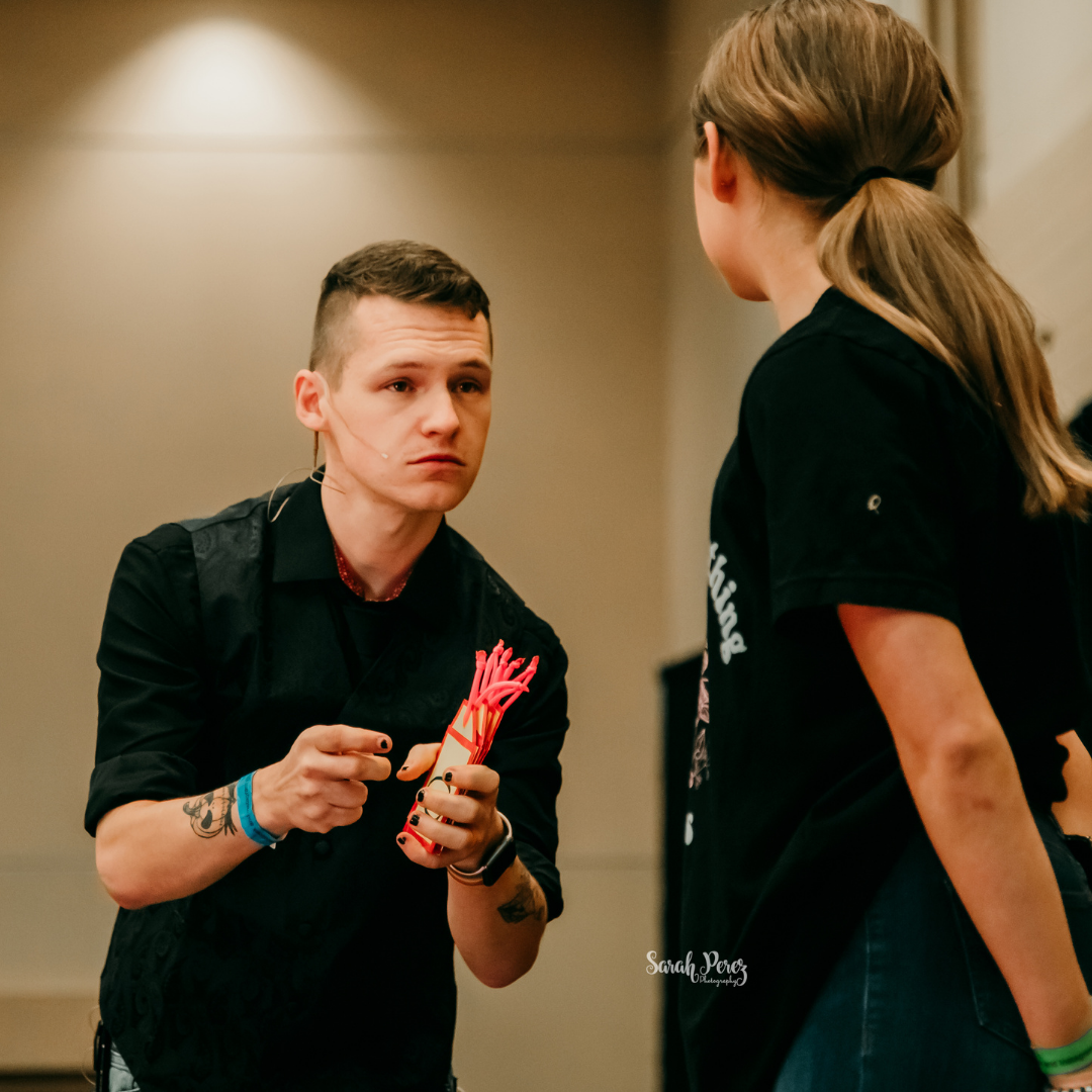 Foggy Jack performing a magic effect with an audience participant on a lit stage