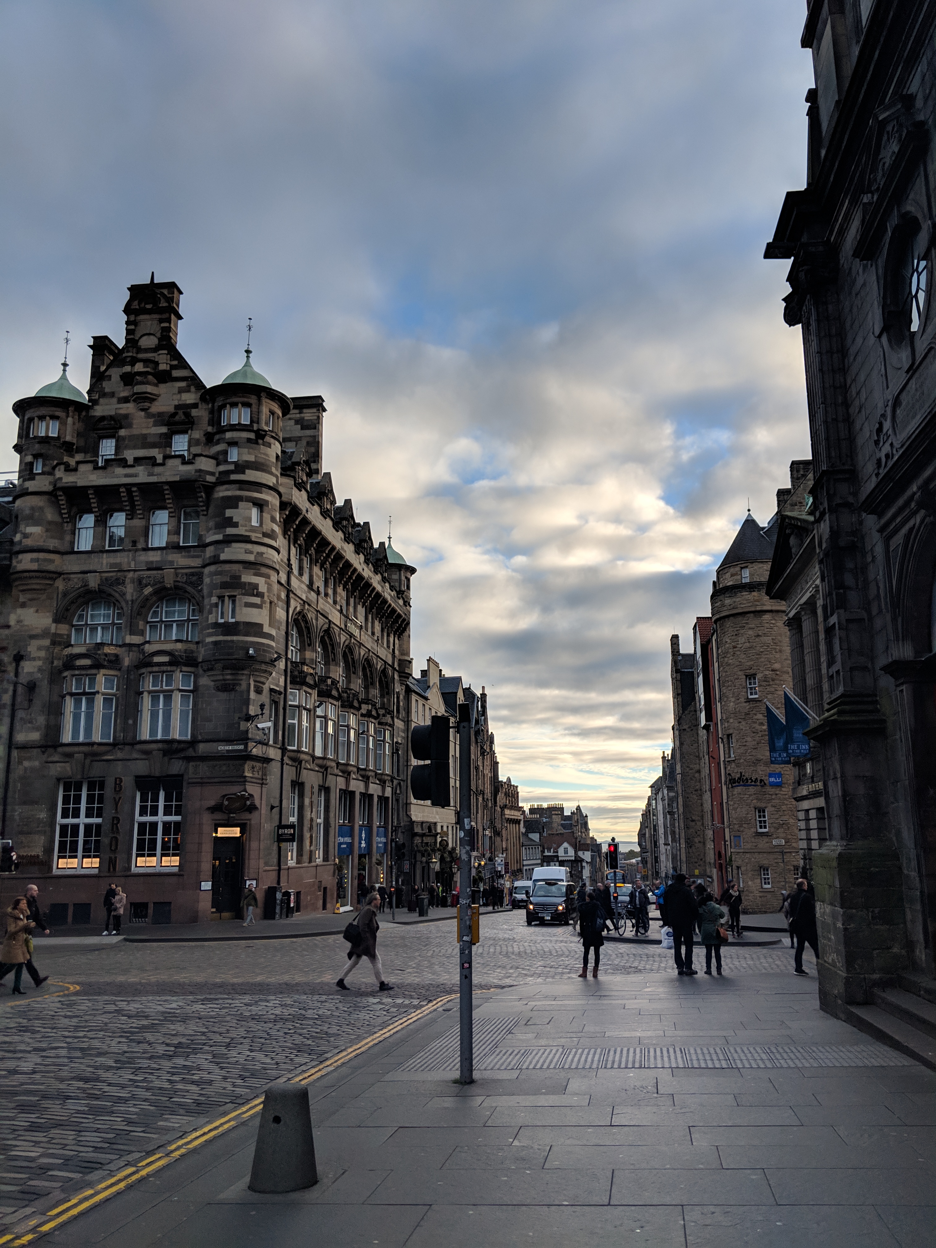 Historic stone buildings lining a cobbled city street beneath a cloudy sky