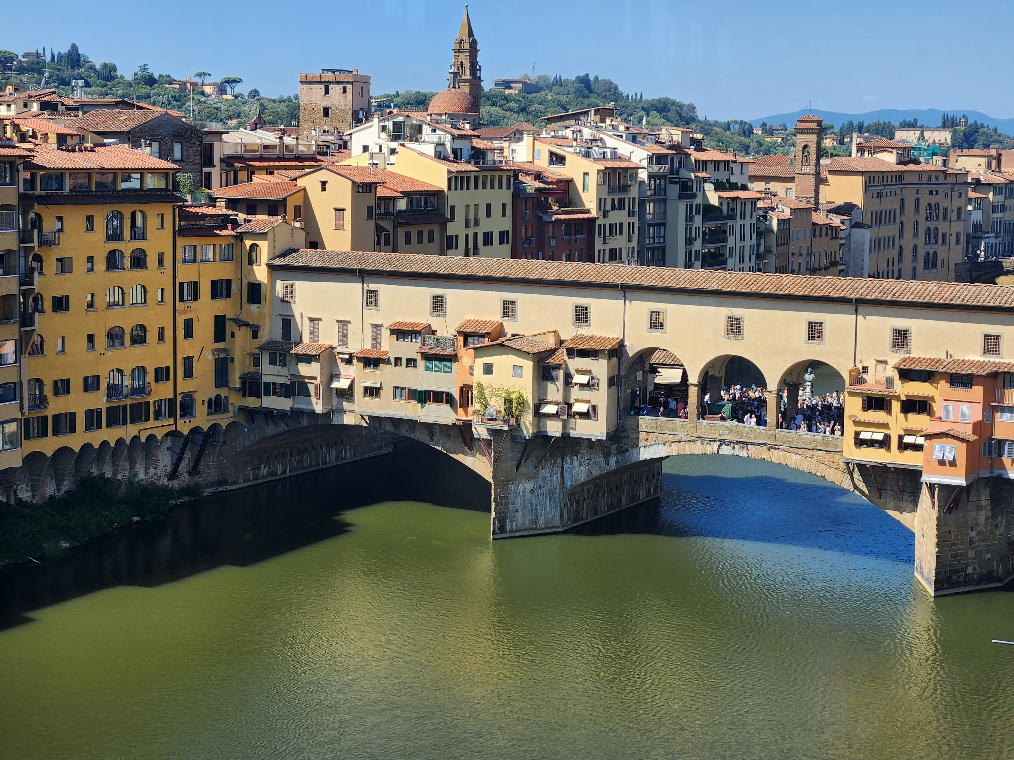 Ponte Vecchio crossing the Arno among terracotta rooftops in Florence.
