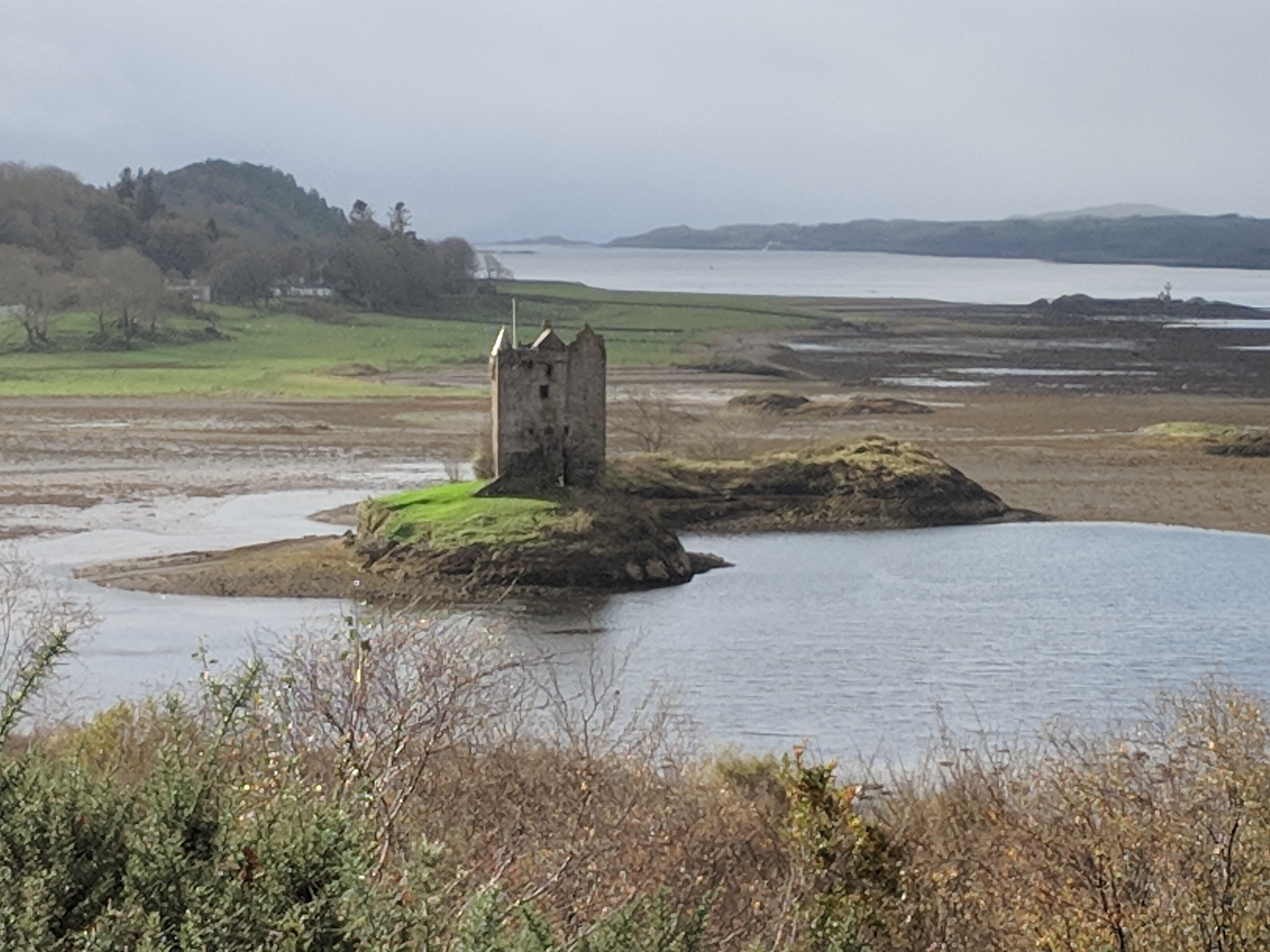 Stone tower on a small island beside a calm coastal inlet