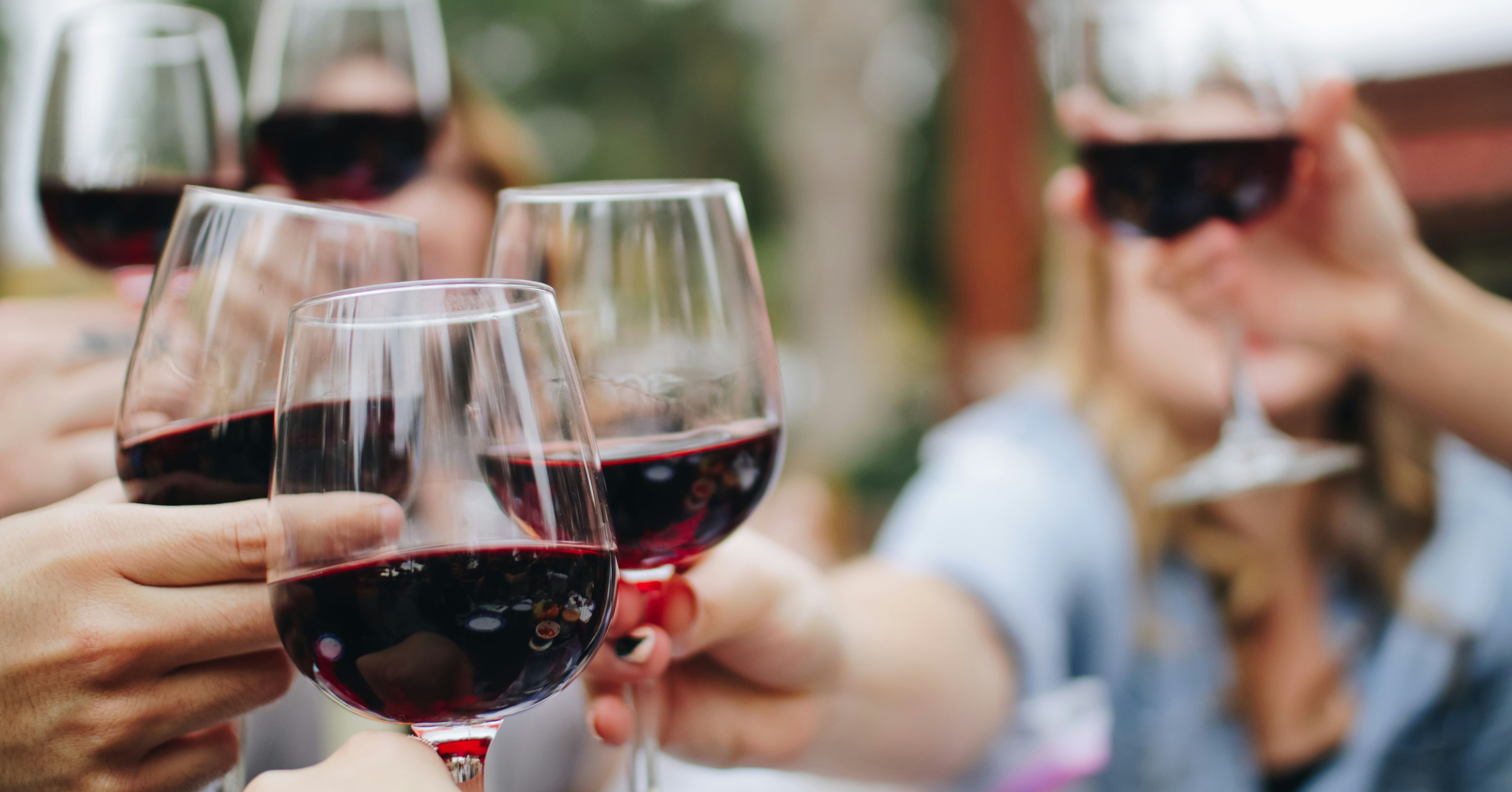 Friends raising glasses of red wine together during a relaxed tasting.