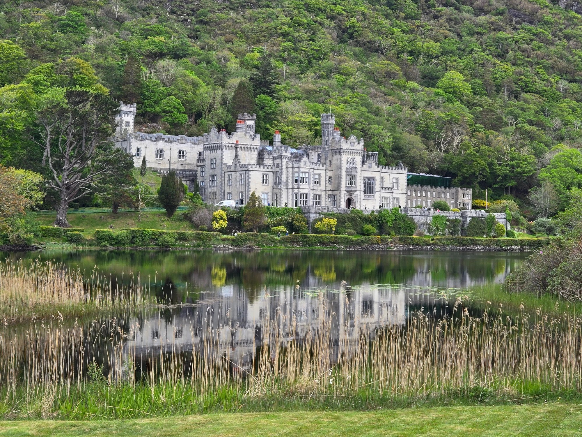 Stone castle beside a lake and wooded hillside