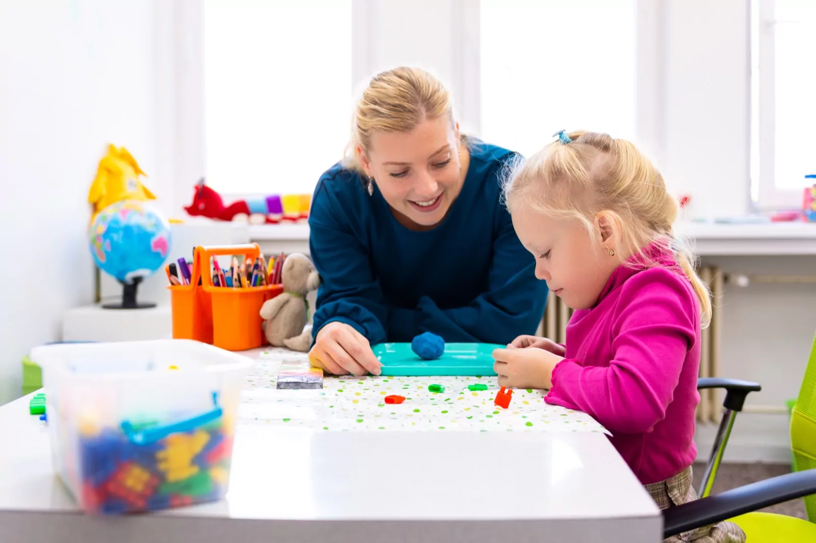 A therapist supports a child with learning activities in a classroom setting.