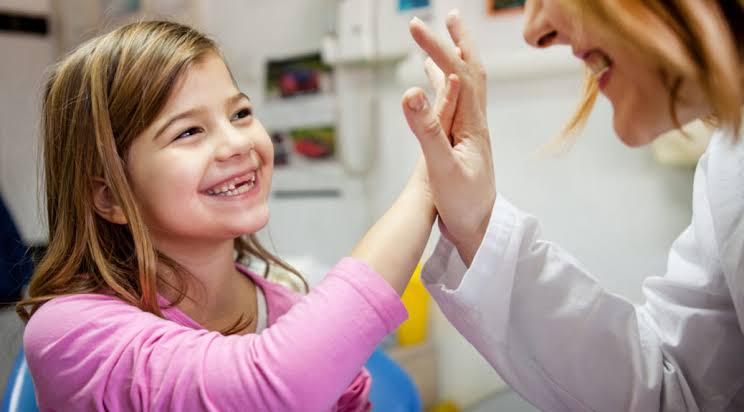 A child smiles while sharing a high-five with an adult during an activity.