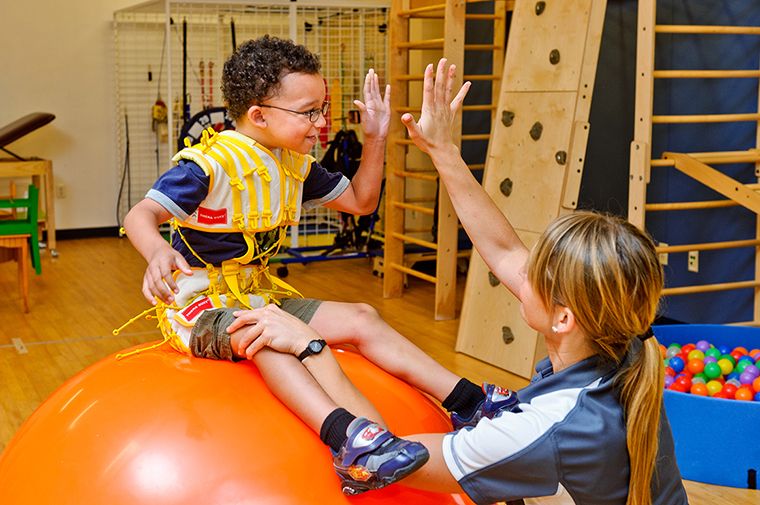 A child and adult share a high-five during a colorful play activity.