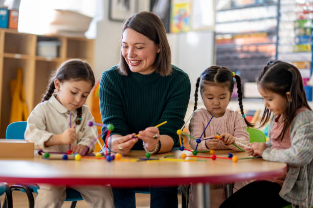 A clinician and children work together with learning materials at a table.