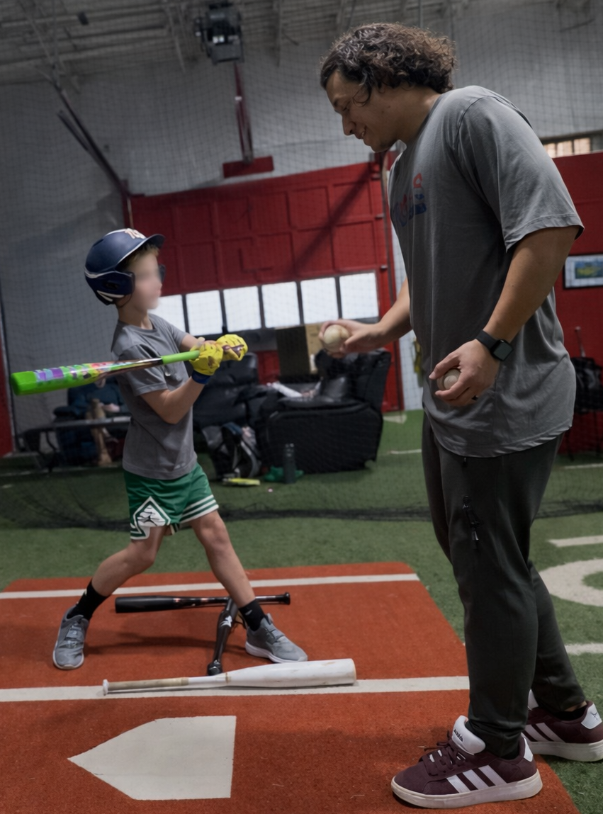 Coach Silvio with young kid batting off tee