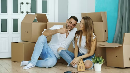 Couple holding house keys and celebrating next to moving boxes on moving day