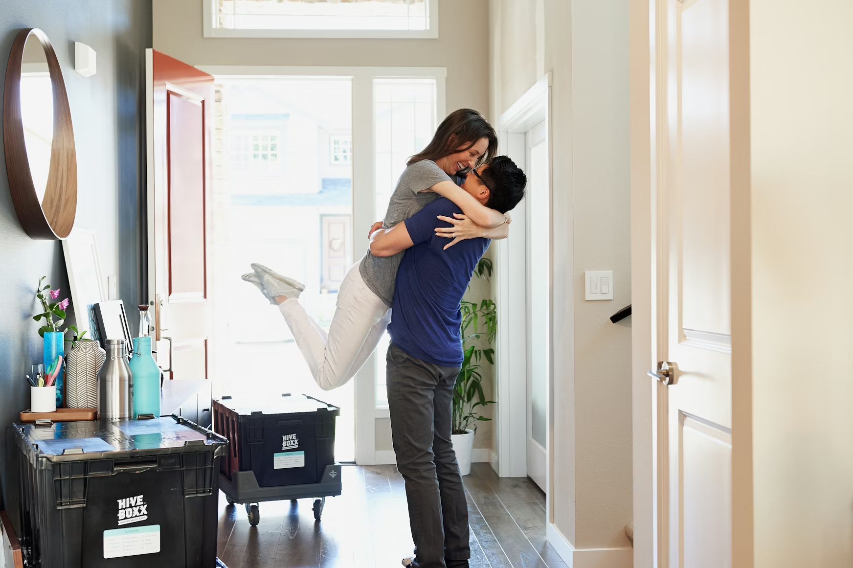 Couple hugging joyfully in the doorway of their new home surrounded by moving boxes