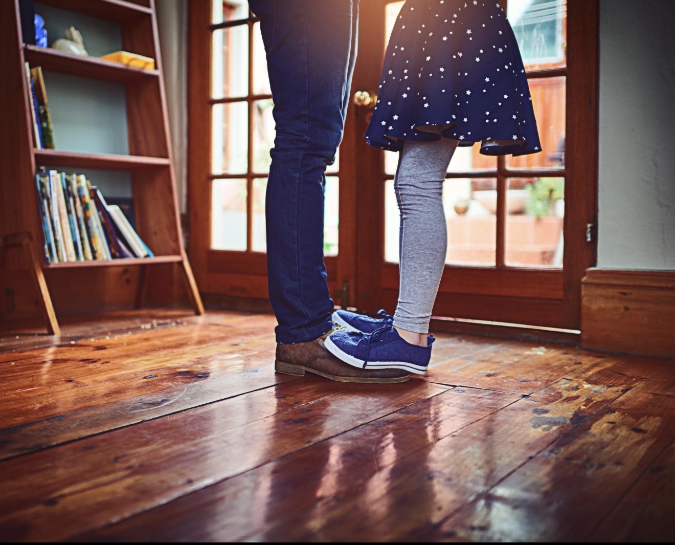 A little girl's feet standing in her father's shoes