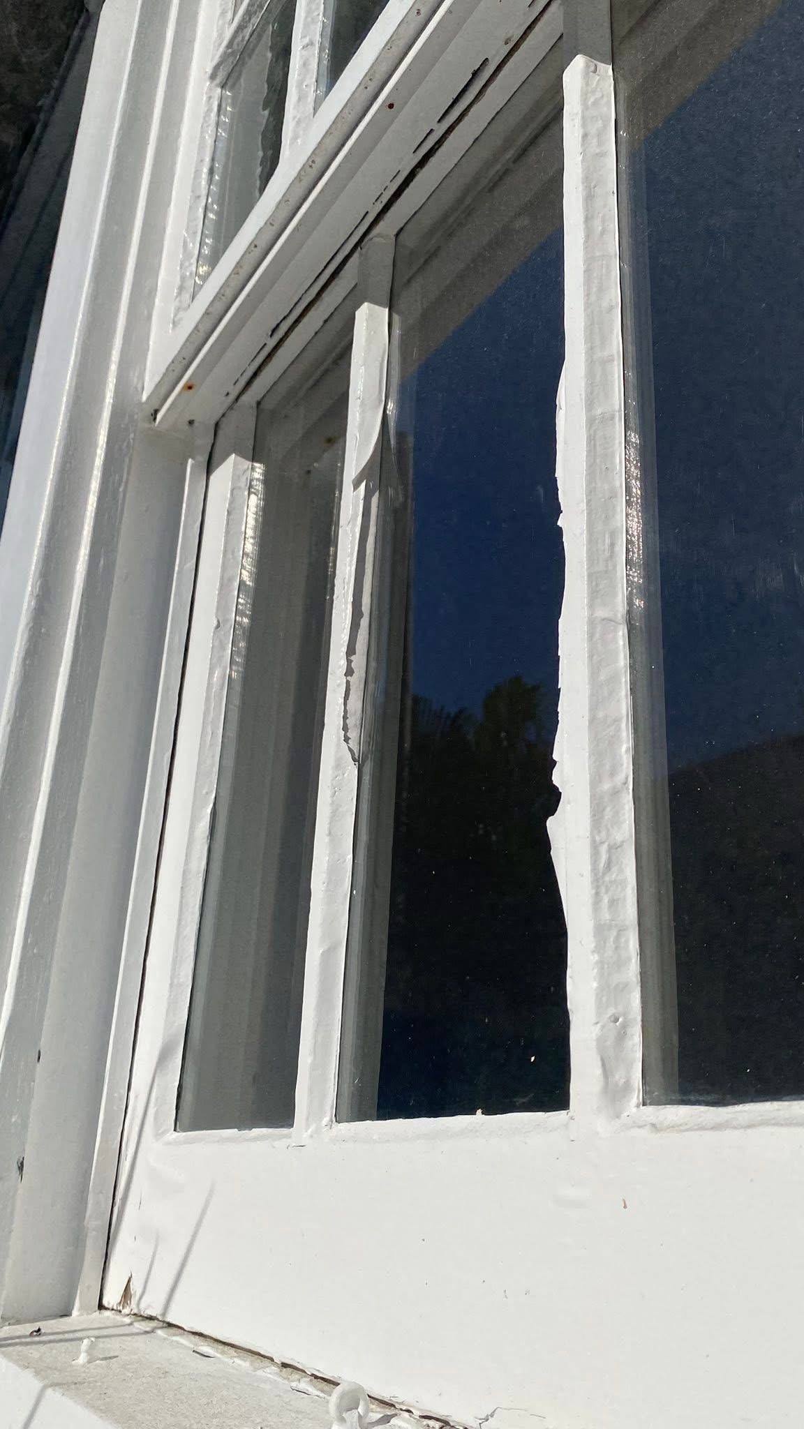 Close-up of wood window muntins with paint cracking and peeling away from the wood surface