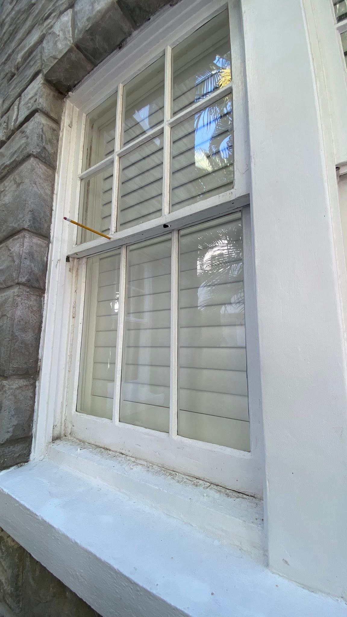 Pencil pushed into the meeting rail of the top sash of a wood window, sinking into rotted wood beneath paint that appears intact from the outside