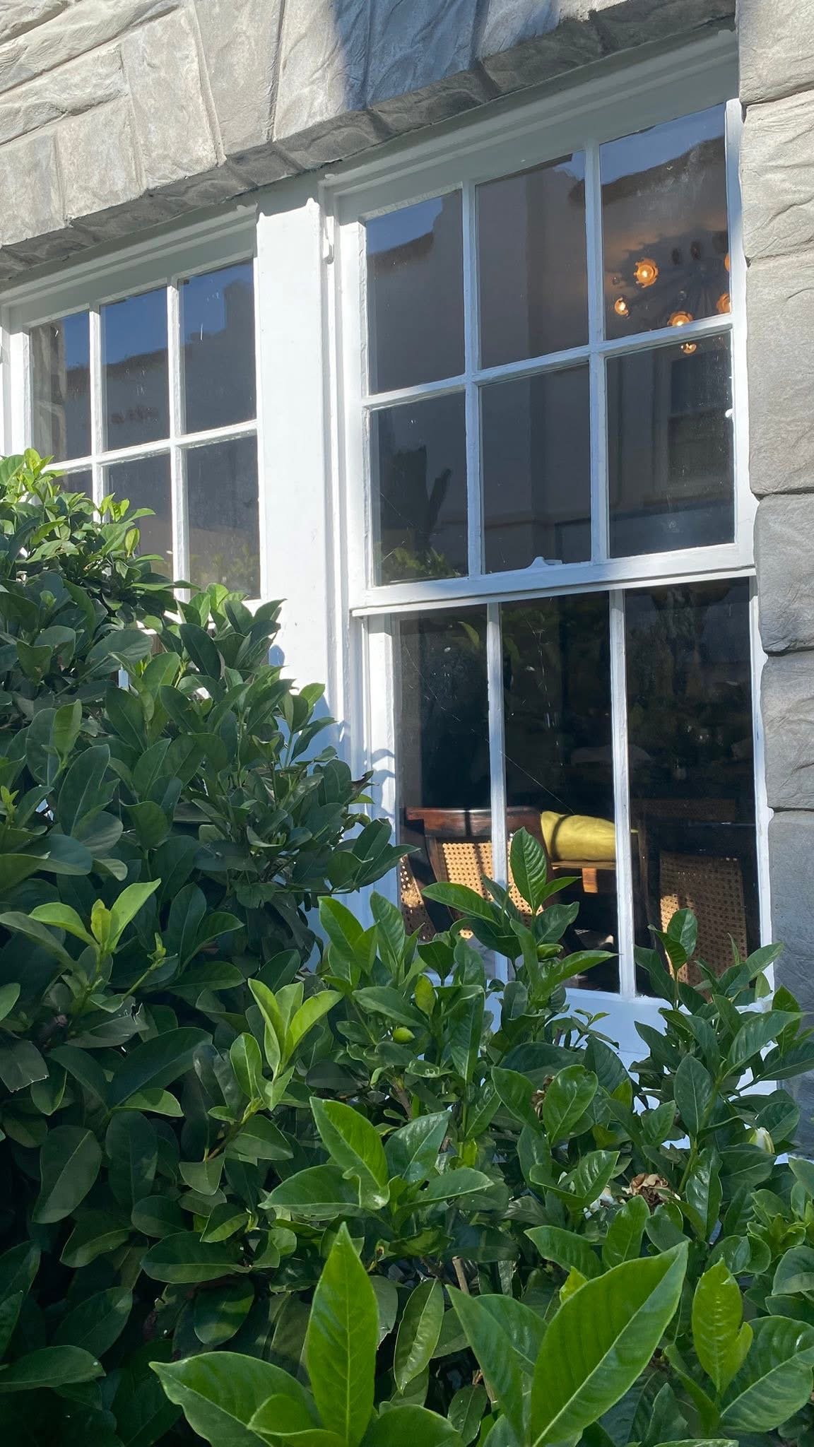 Full wood window view against a stone facade, with paint in varying states of condition