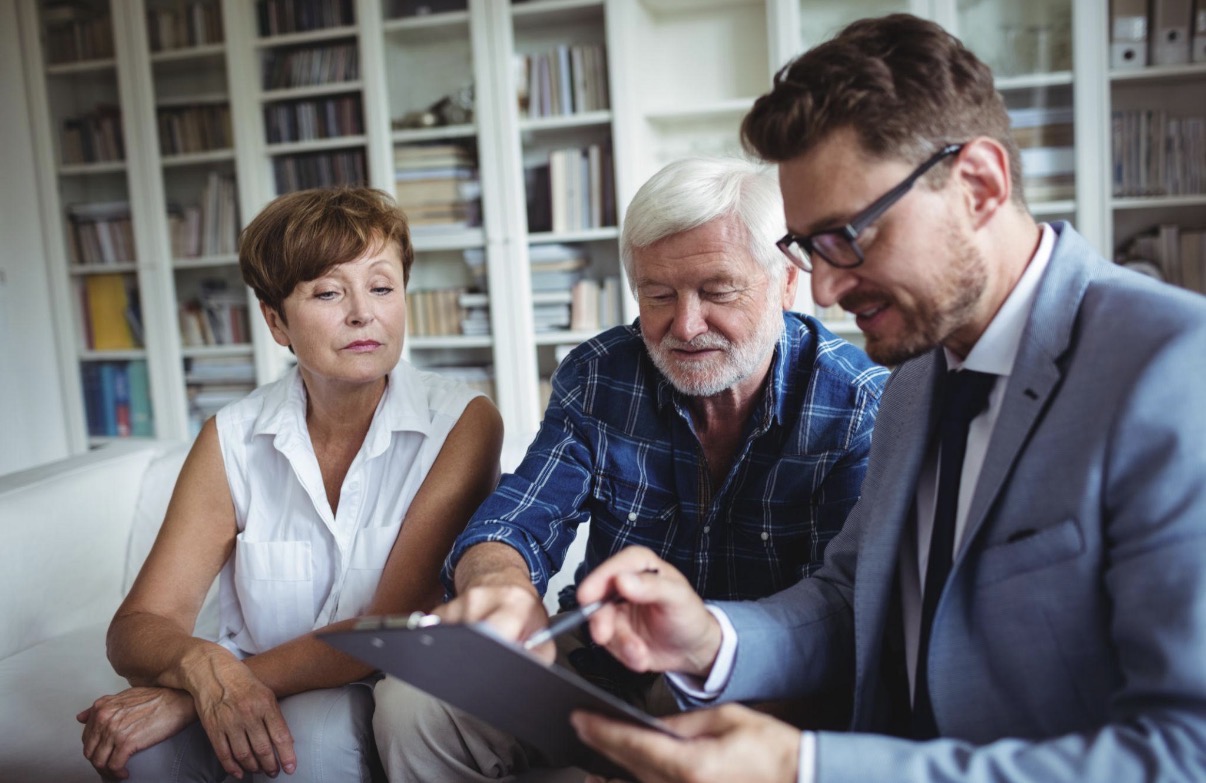 Senior couple reviewing Medicare options with their advisor in a warm home setting