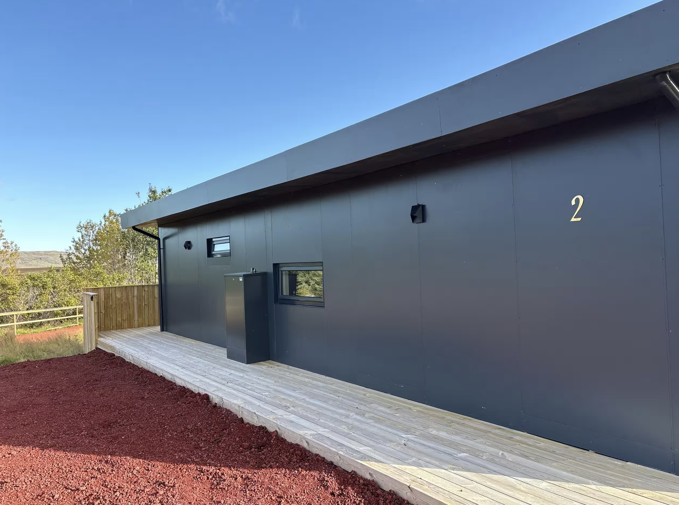 Exterior of the dark accommodation building marked 2, with Icelandic hills beyond.