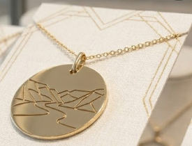 The Landscape Disc Pendant — geometric mountain and river engraving on a gold disc