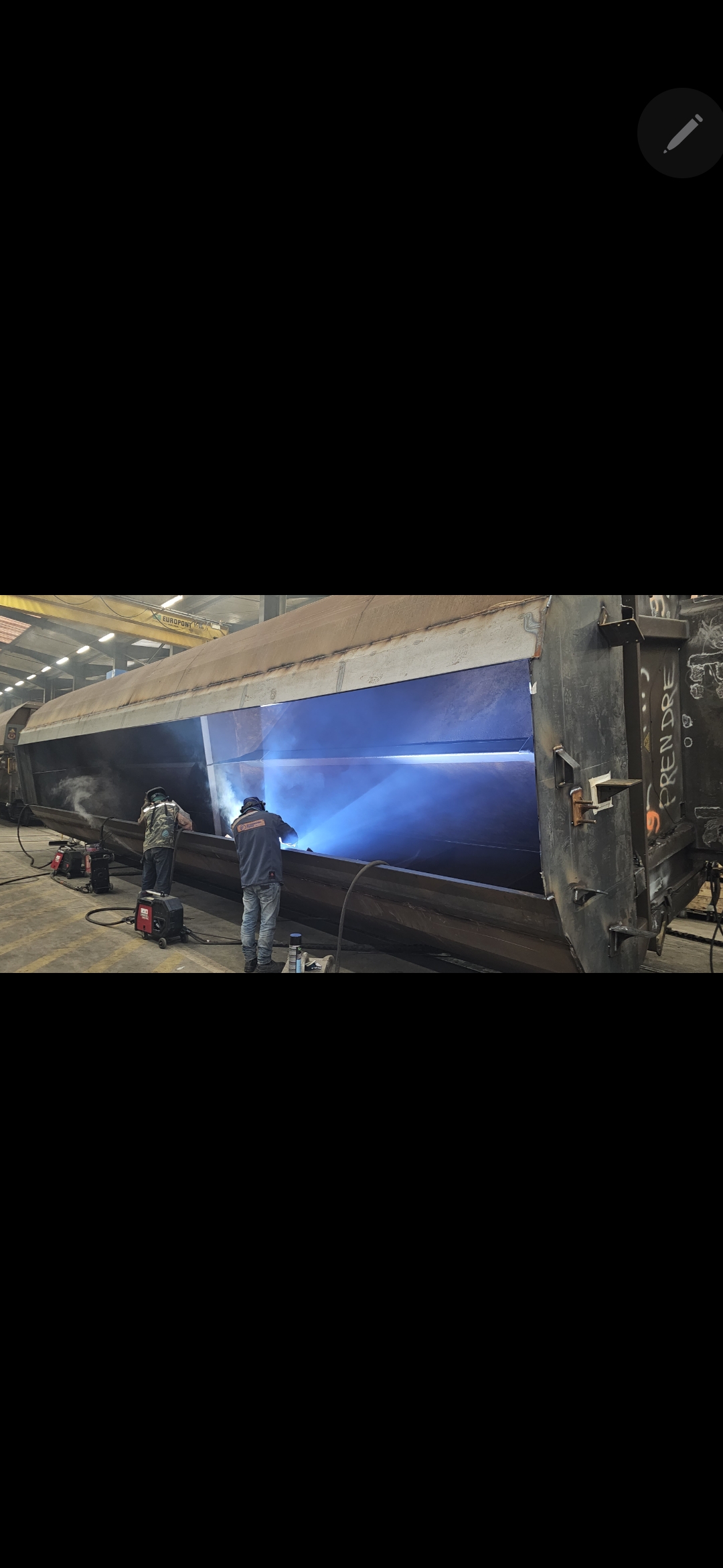Deux soudeurs en action sur wagon, arc bleu intense