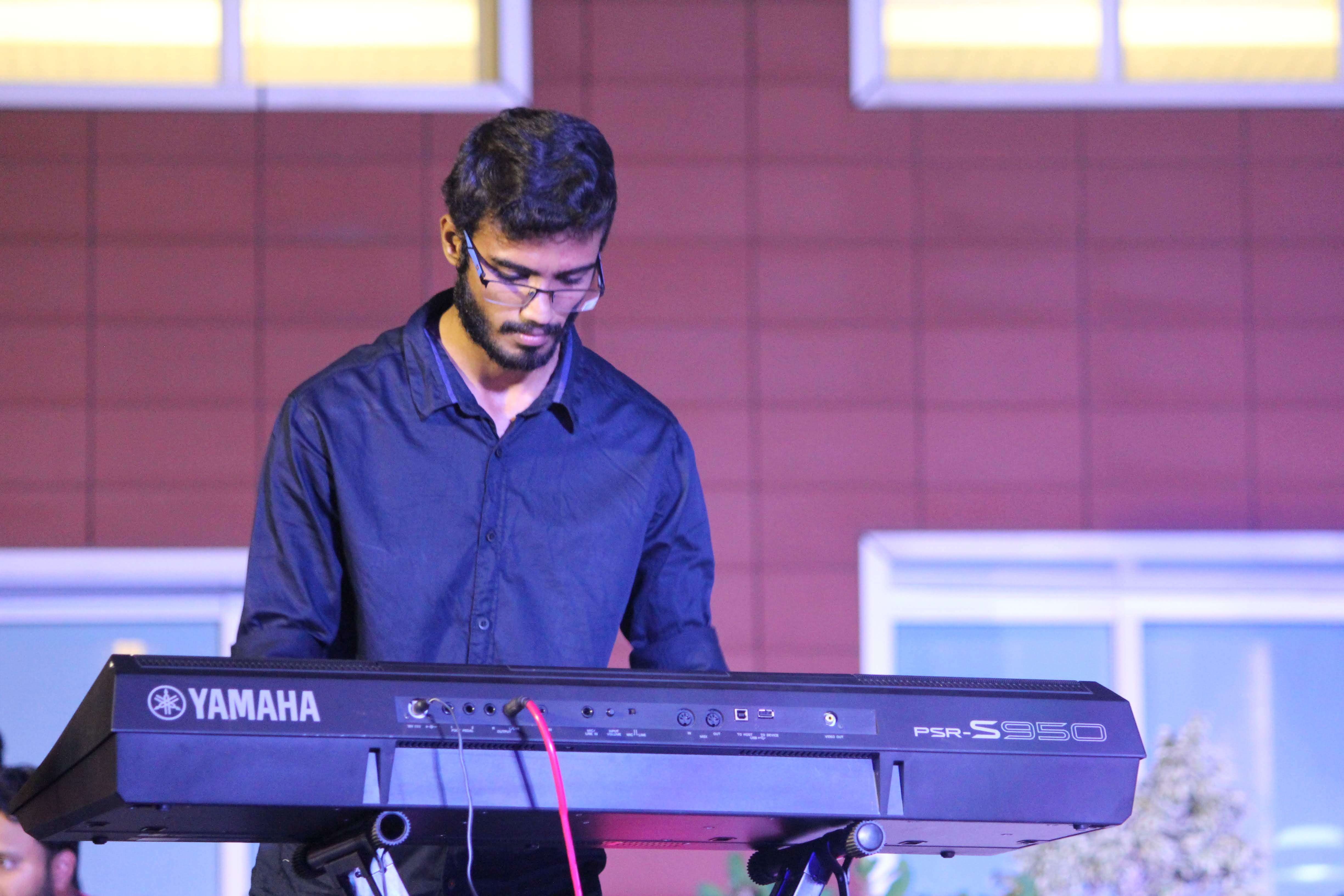 Yashodeep performing on stage with Yamaha PSR-S950 under blue and purple lights