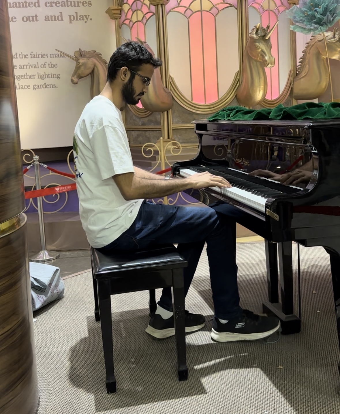 Yashodeep playing a grand piano casually at an ornate venue in a t-shirt