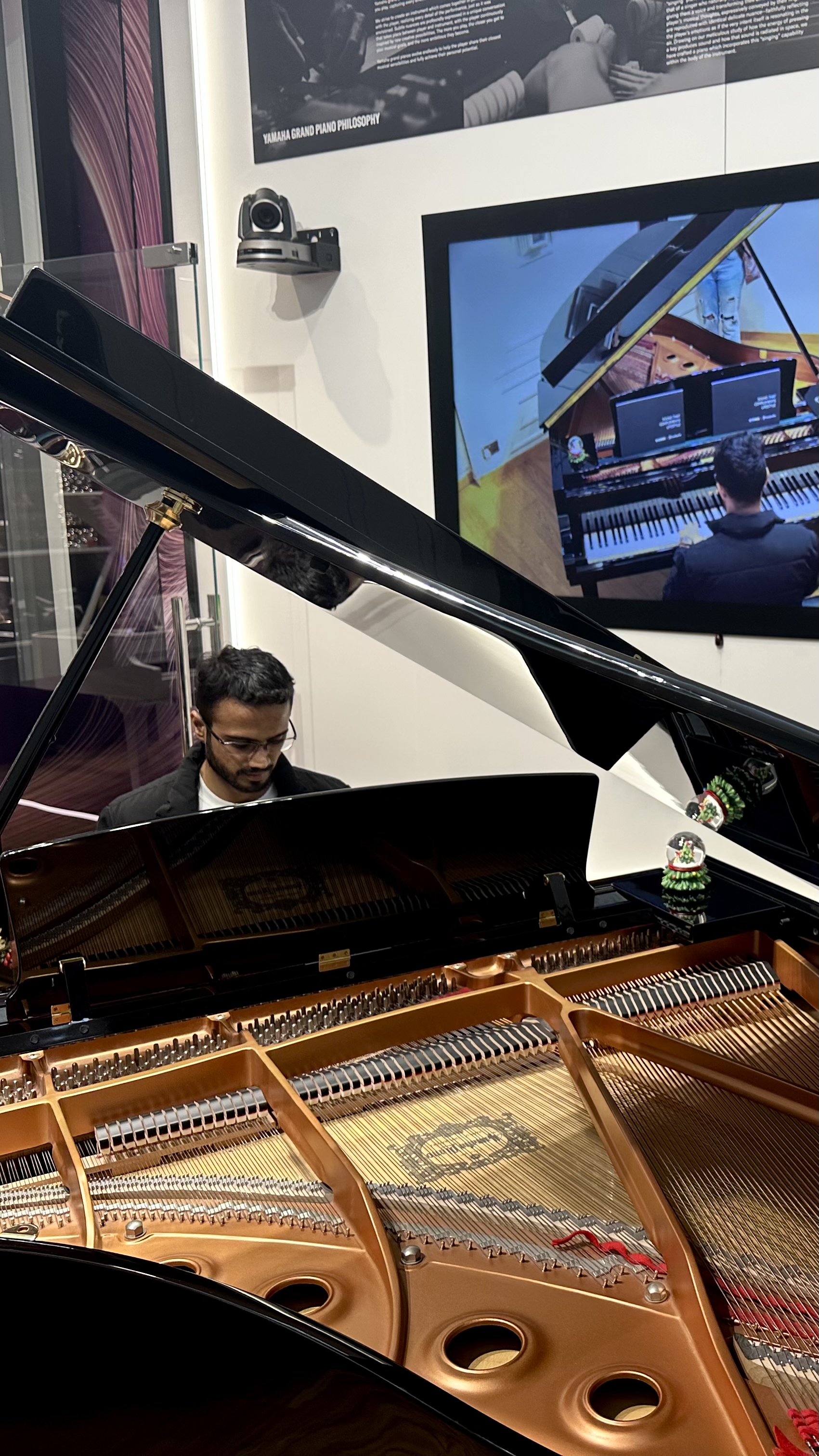 Yashodeep playing at a Yamaha Grand Piano showroom, Yamaha Grand Piano Philosophy sign visible
