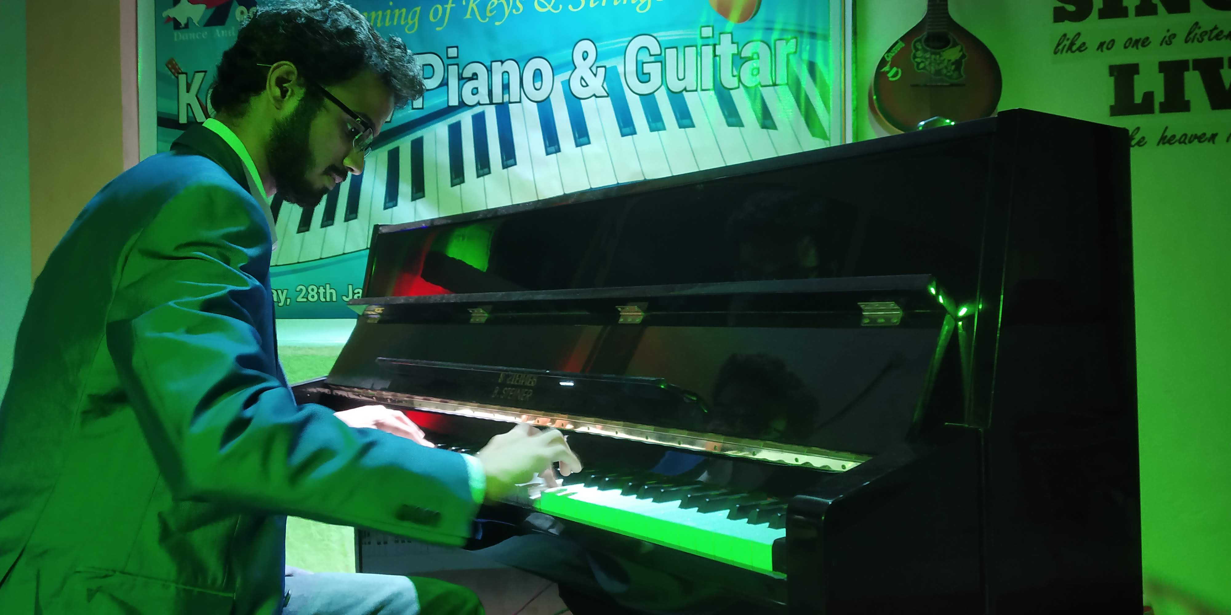 Yashodeep performing at a formal piano concert under green stage lights