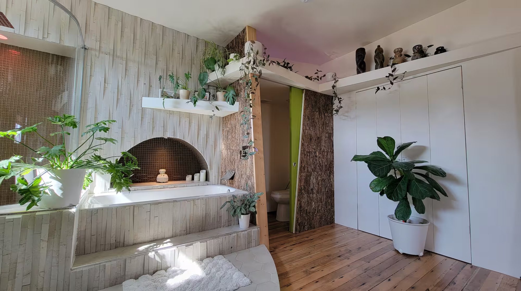 Soaking tub alcove — arched niche, bamboo and stone tile, plants and sculptures