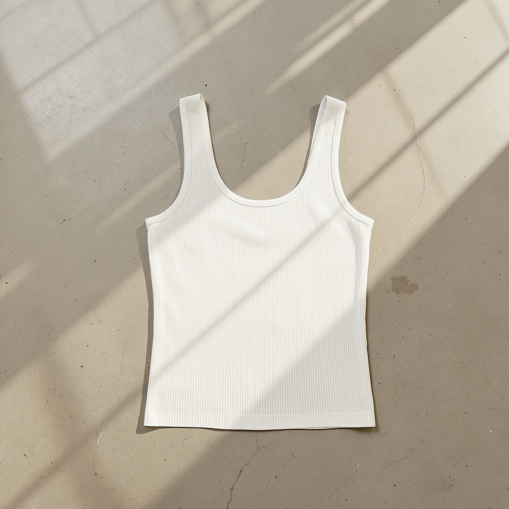 The Soft Layer Tank ribbed cream tank on concrete floor, clean minimal Everlane aesthetic